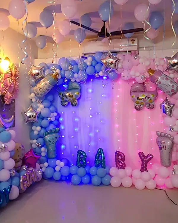 A full-room baby shower decoration with a "Boy or Girl" theme. The setup is split into blue and pink sections, each with its own balloon garland, shimmer curtain, and themed foil balloons like baby carriages and footprints.