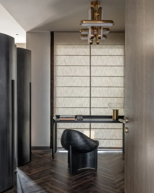 A glimpse into a study nook in the Aikaa villa. The sculptural black chair, minimalist desk, and elegant brass lighting create a workspace that is both functional and highly stylish.