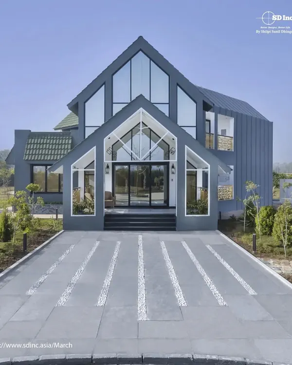The stunning front elevation of our modern farmhouse project in Sohna, Gurugram. This architectural design features large glass panels and a distinctive A-frame structure to create a home that is both grand and welcoming.
