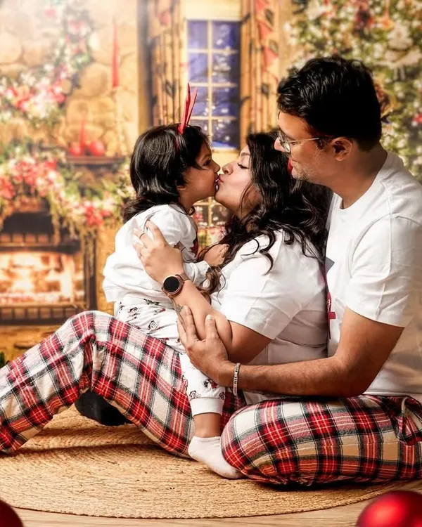 A sweet family kiss in front of our cozy Christmas fireplace backdrop. Our holiday mini sessions are perfect for creating photos for your annual cards and making lasting memories.