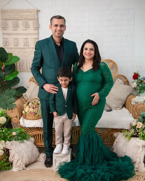 A picture-perfect family portrait. The coordinating green outfits, the proud parents, and the excited big brother create a harmonious and heartwarming image. This is a beautiful way to document the family just before it grows.