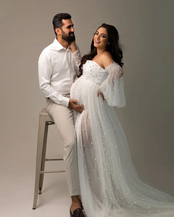 A joyful, candid moment during an elegant couple's maternity shoot. Her smile says it all, surrounded by the soft tulle of her beautiful gown.
