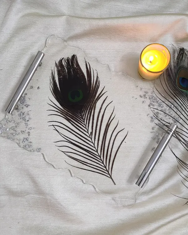 This custom tray features a single, striking peacock feather preserved in clear resin. The silver handles and flakes add a modern touch to this nature-inspired piece.