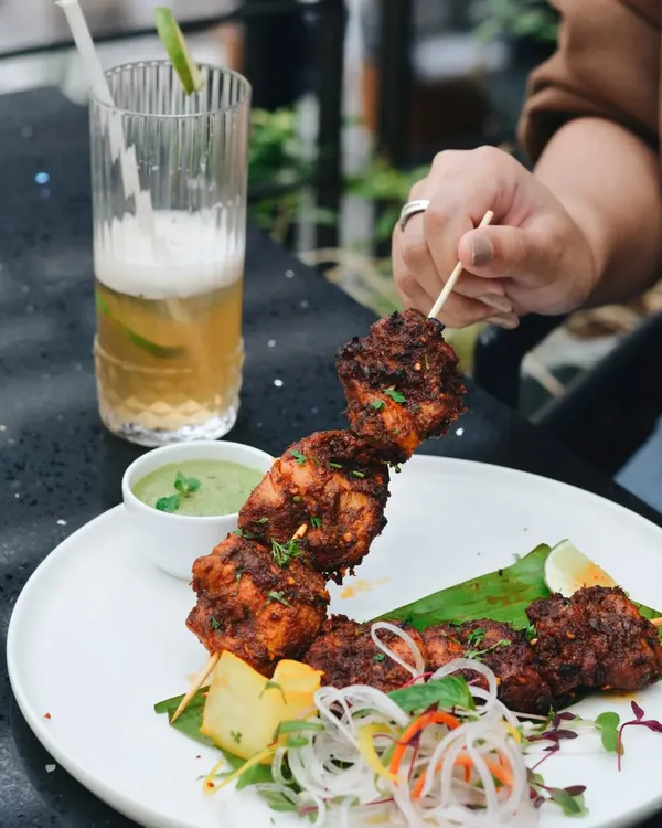 Capturing people with food is one of my favorite genres. This shot of a person holding a chicken skewer at a restaurant table brings the dish to life and creates a relatable, happy moment.