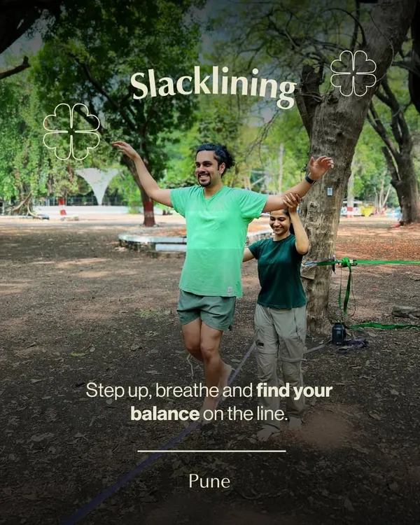An instructor helps a participant find his balance during a slacklining session in Pune. This activity is a fantastic way to improve focus and core strength while enjoying the outdoors.