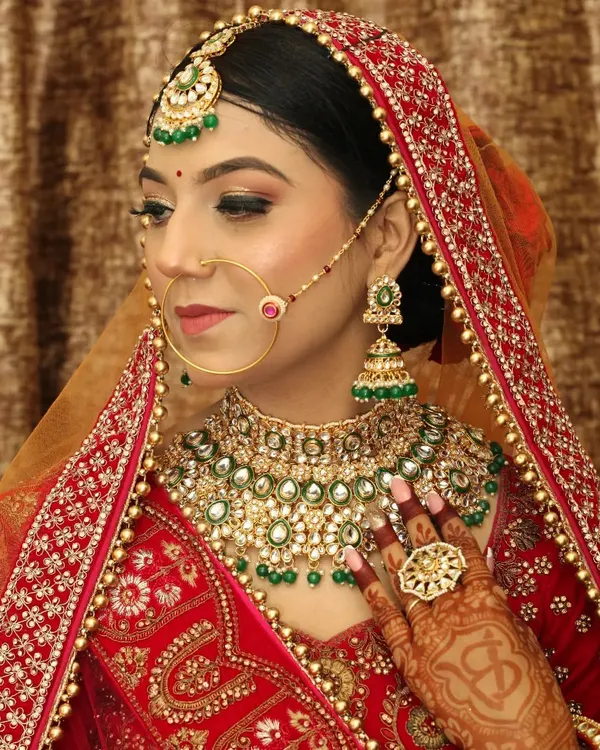 A classic three-quarter bridal portrait, showcasing the complete look from her elaborate dupatta to the henna on her hands. This is a must-have traditional wedding shot for the family album.