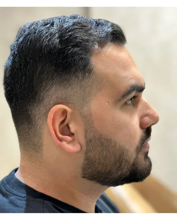 A close-up of a perfect skin fade. This image showcases the precision and skill required for a seamless blend, paired with a sharp beard lineup.
