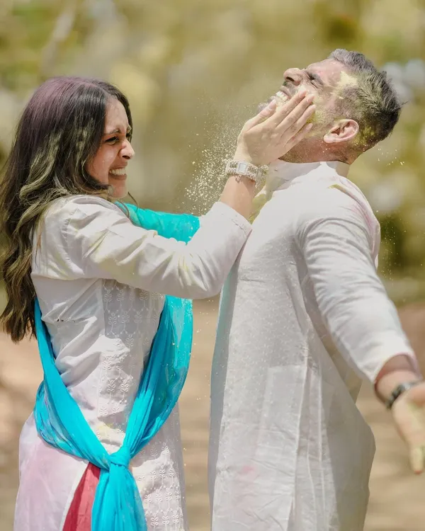 A moment of pure, uninhibited fun during a Holi-themed pre-wedding shoot, as she playfully smears color on his face.
