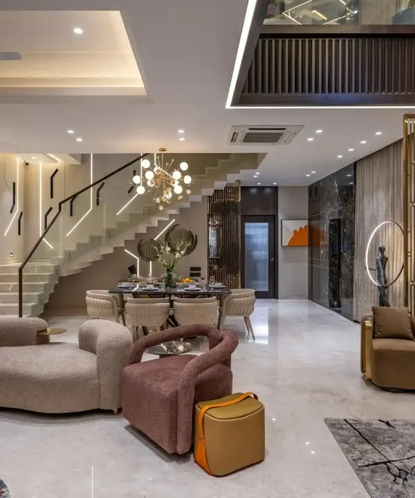 This duplex living room combines dramatic lighting on the staircase with plush, curved sofas to create a dynamic yet inviting atmosphere. We used dark marble and metallic accents to add a layer of opulence and connect the different zones.