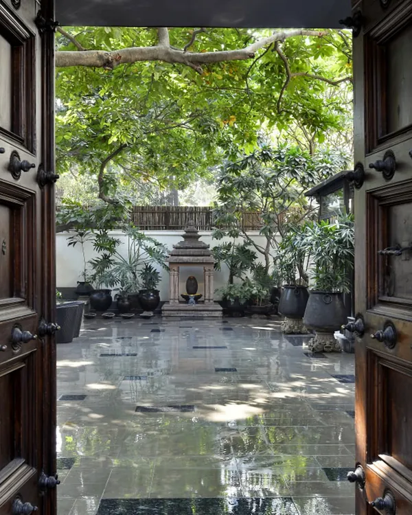 The entrance to our Golf Links Courtyard Home, framed by antique Chettinad doors. This view opens into the central courtyard, a tranquil space that serves as the heart of the home, connecting the various living areas.