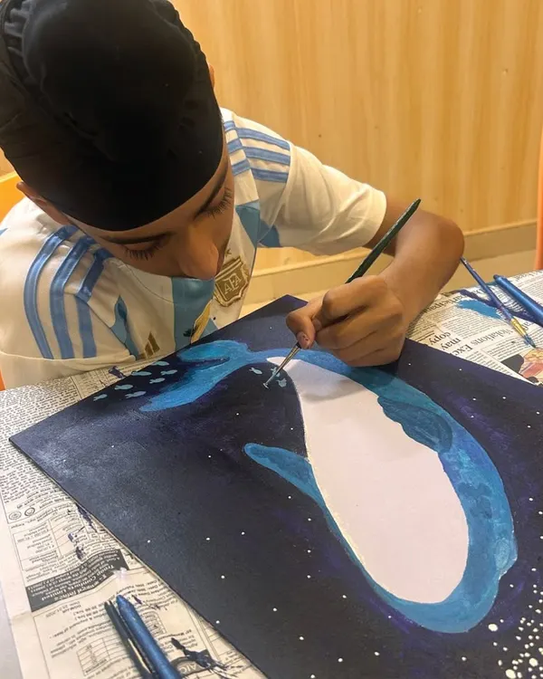 Concentration is key. This young artist is meticulously adding the final touches to his deep-sea whale painting, learning about fine brush control and detail work.