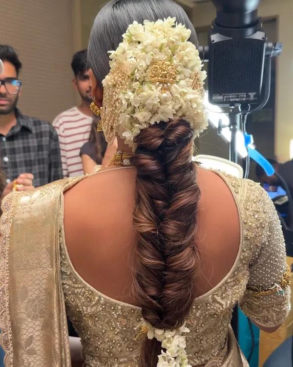 A behind the scenes look at the stunning South Indian bridal braid, showing the intricate fishtail plait before all the floral arrangements are added. This highlights the foundational skill required for such a detailed look.