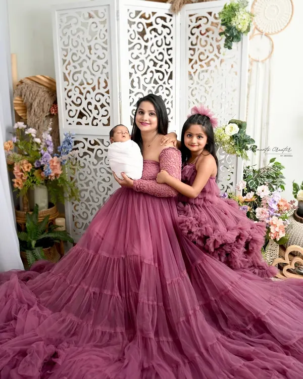 A picture of pure elegance with mom, big sister, and the new baby in matching ruffled gowns. This portrait showcases the beautiful bond between the leading ladies of the family in our floral studio setup.