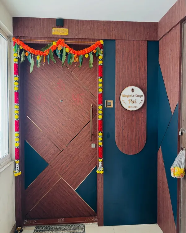 A modern main door with a geometric pattern and a two-tone wood and dark blue finish. The custom round nameplate adds a personalized and welcoming touch.