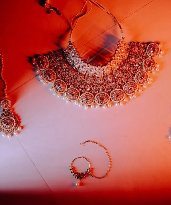 A beautifully styled shot of the bride's wedding jewelry. Capturing these details, like the necklace, earrings, and nath, is essential to telling the complete story of her bridal look.