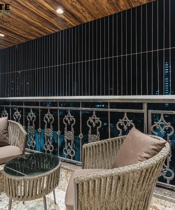 A beautifully designed balcony in Seawoods, perfect for enjoying an evening. The space features comfortable wicker chairs, a wood-paneled ceiling, and an ornate metal railing, turning a simple balcony into a private retreat.