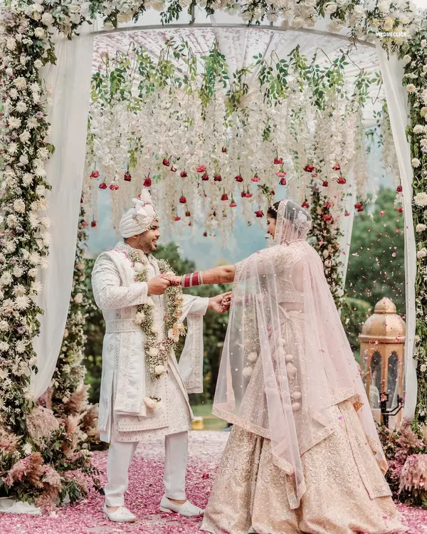 The pivotal Varmala moment, framed by a stunning floral arch at this beautiful outdoor wedding. This is where two worlds officially meet, and I capture it with all the grandeur it deserves.