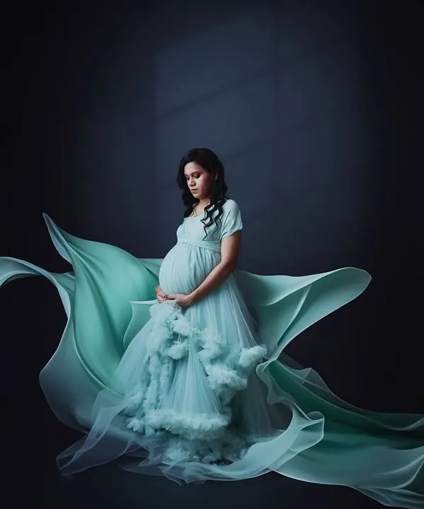 This fine art maternity portrait uses dramatic lighting and a flowing gown to create a powerful, elegant image. We specialize in these low-key, artistic shots that transform your pregnancy photo into a piece of art.