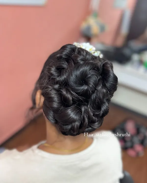 An intricate updo featuring multiple sculpted rose shapes, creating a stunning floral bouquet effect with the hair. This is a highly skilled and artistic style for a bride.