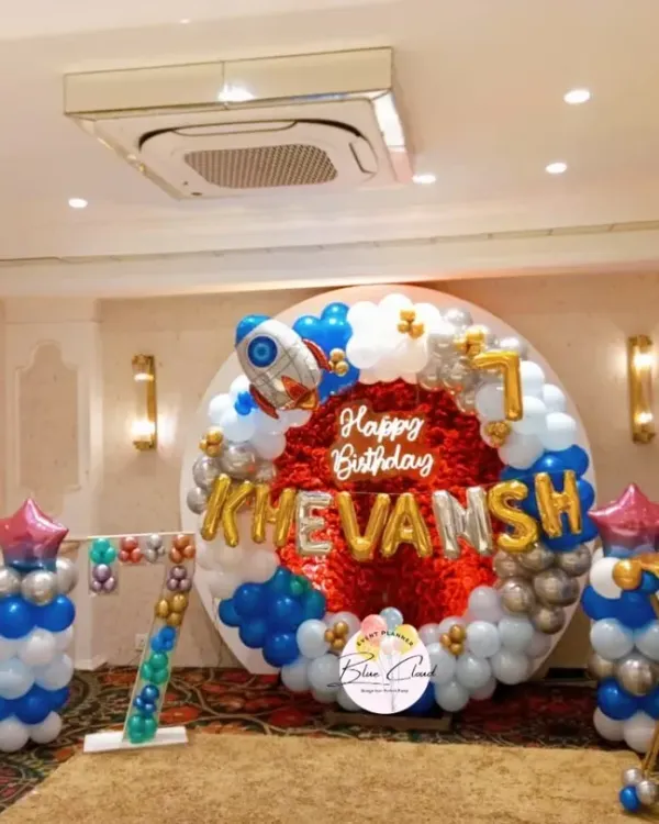 An outer space themed birthday party for a 7th birthday. We created this balloon ring with a red foil backdrop, a rocket ship balloon, and a marquee number '7'.