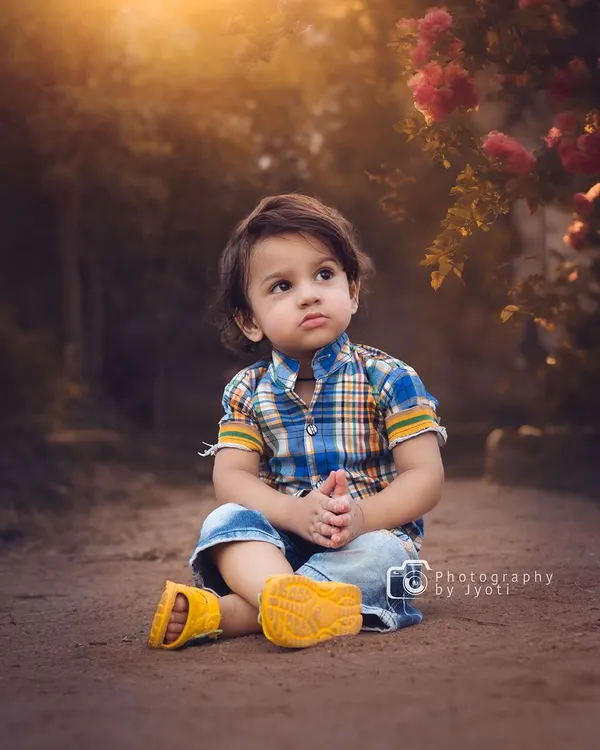 A thoughtful portrait of a young boy sitting on a rustic path, with the warm glow of the setting sun creating a beautiful, soft light. Outdoor sessions are perfect for capturing these serene moments.