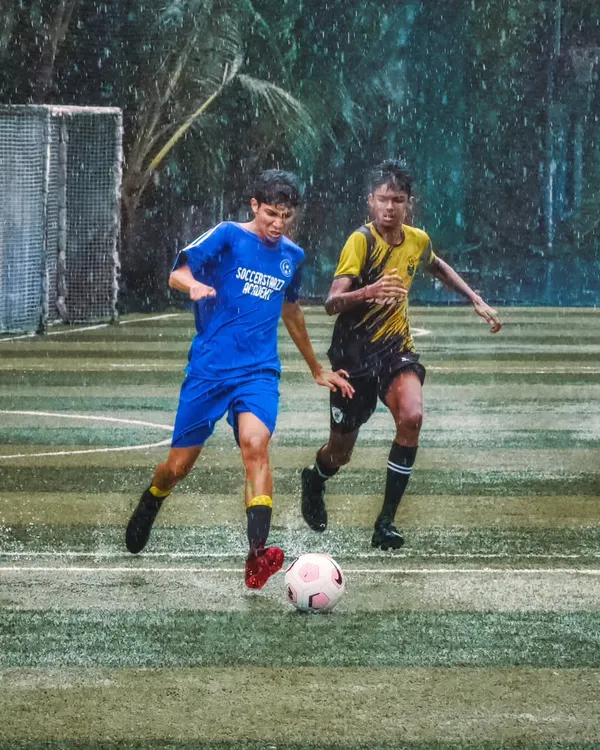 Rain or shine, the game goes on. An U-16 player skillfully dribbles the ball down a wet turf during the Independence Cup, showing determination against a defender.