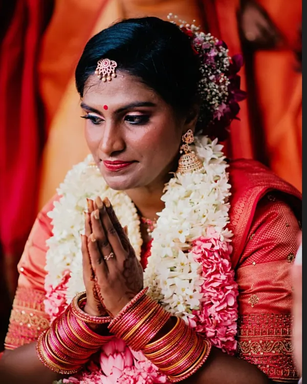 A serene moment of a South Indian bride during her Muhurtham ceremony. I created a cut crease eye with golden and pink shimmer to complement her traditional red saree, focusing on a radiant finish for her brown skin.