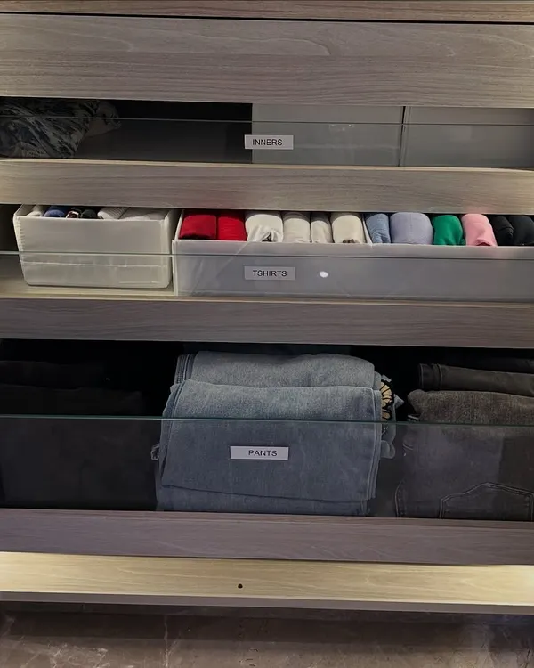 This is our signature drawer system in action. We use clear labels and vertical folding to organize pants, t-shirts, and innerwear. This method ensures you can see everything you own in a single glance.