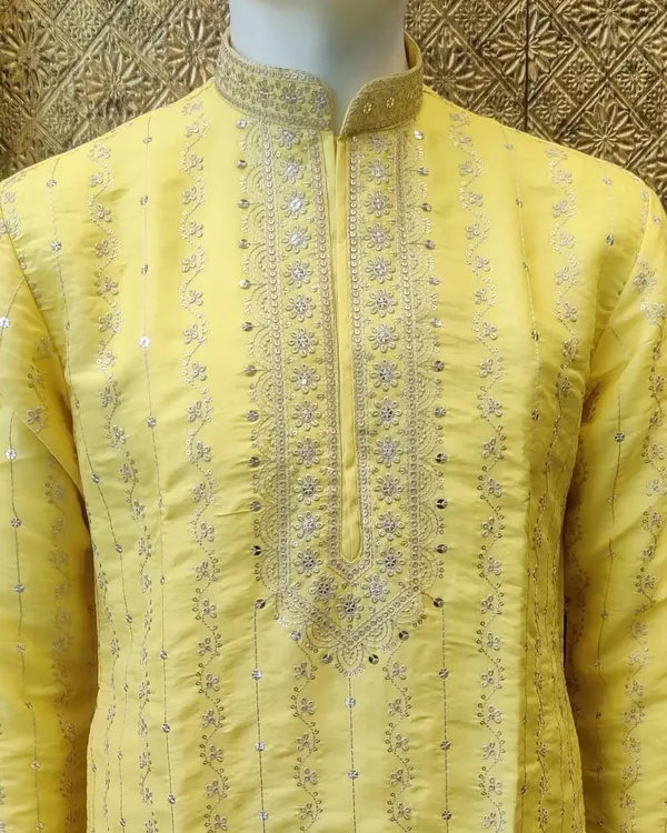 A vibrant yellow kurta, perfect for a Haldi ceremony. This piece features delicate silver embroidery around the neckline and placket, adding a touch of festive elegance.
