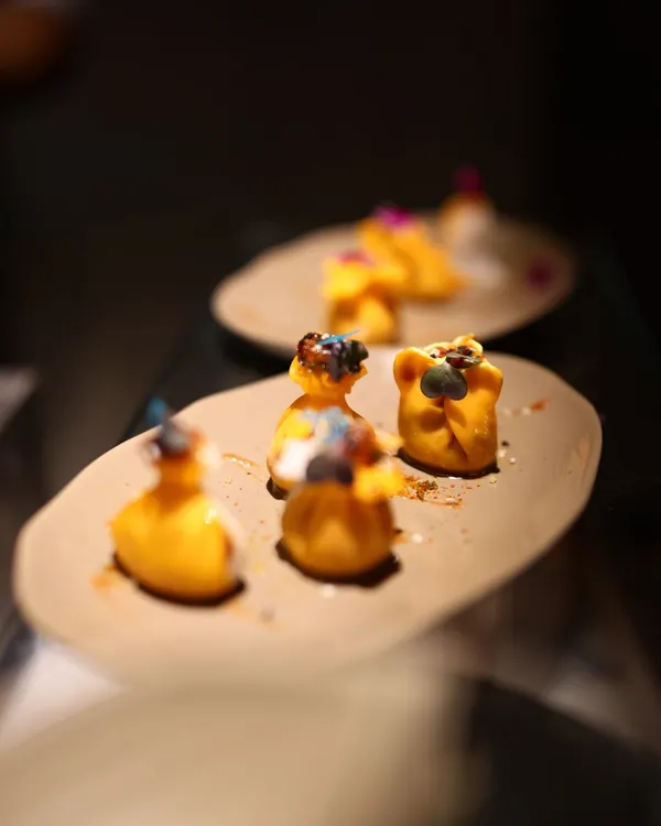 These delicately crafted dumplings, garnished with micro-herbs and spices, are an example of our artistic approach to appetizers. Each piece is a bite of flavor, presented on minimalist earthenware to highlight the food itself.
