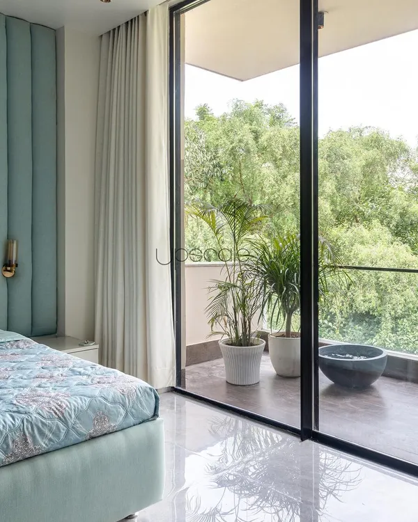This bedroom was designed to feel like a retreat. The large, sliding glass door opens onto a private balcony, allowing the sights and sounds of the lush green outdoors to become a part of the room's serene atmosphere.