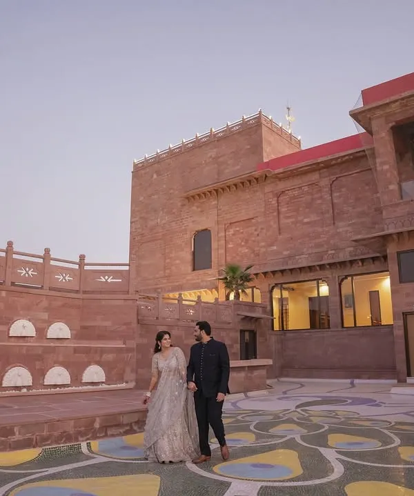 A magnificent wide shot of the couple in the courtyard of the Radisson Hotel Jodhpur. The grand scale of the heritage architecture provides a stunning, regal backdrop for their pre-wedding photos.