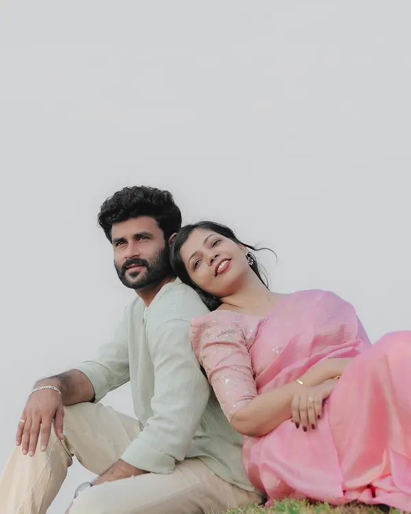 A serene moment for the couple, sitting back-to-back in a field with a clean, bright background. The simplicity of the shot emphasizes their connection.
