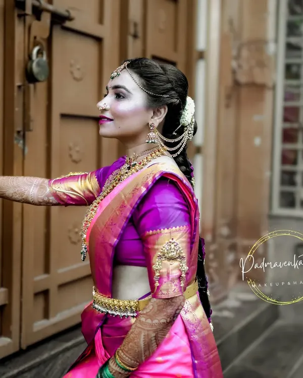 A beautiful side profile of a South Indian bride, showcasing the intricate hairstyle adorned with traditional hair jewelry and the flawless, glowing makeup that lasts through all the wedding rituals.