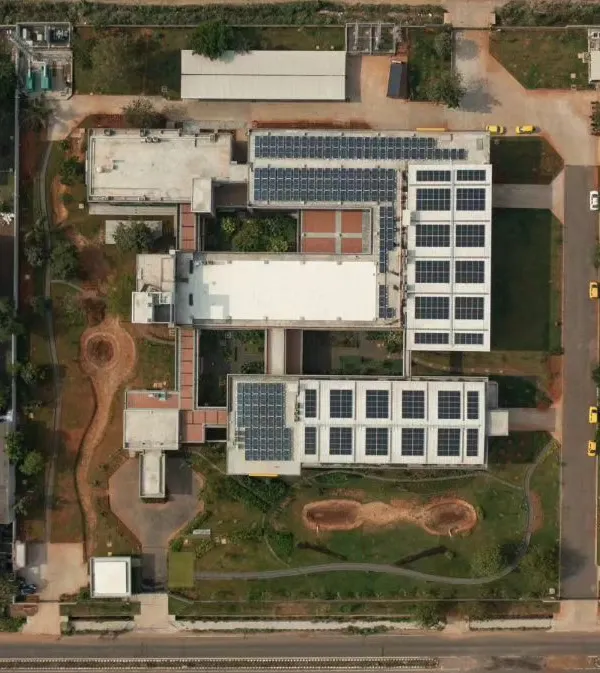 An aerial top-down view of the Fanuc India factory in Chennai. This project won an award for sustainability, incorporating features like extensive solar panels, rainwater harvesting, and green courtyards within the industrial complex.
