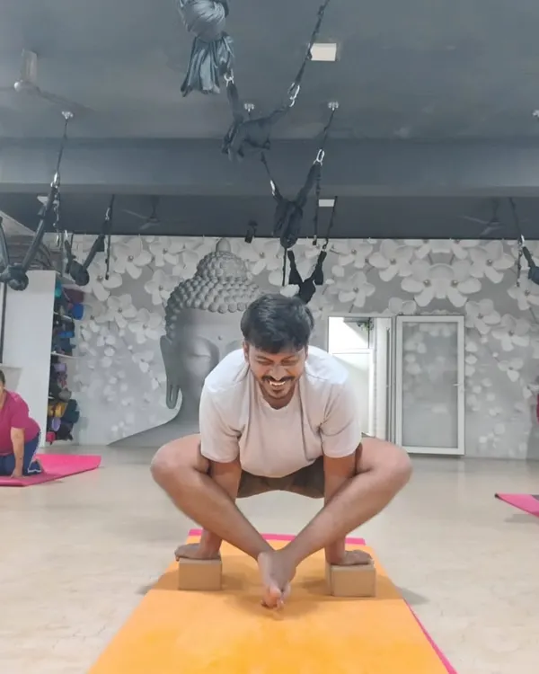 A student demonstrates focus and strength, using blocks for balance in a variation of Malasana (Garland Pose).