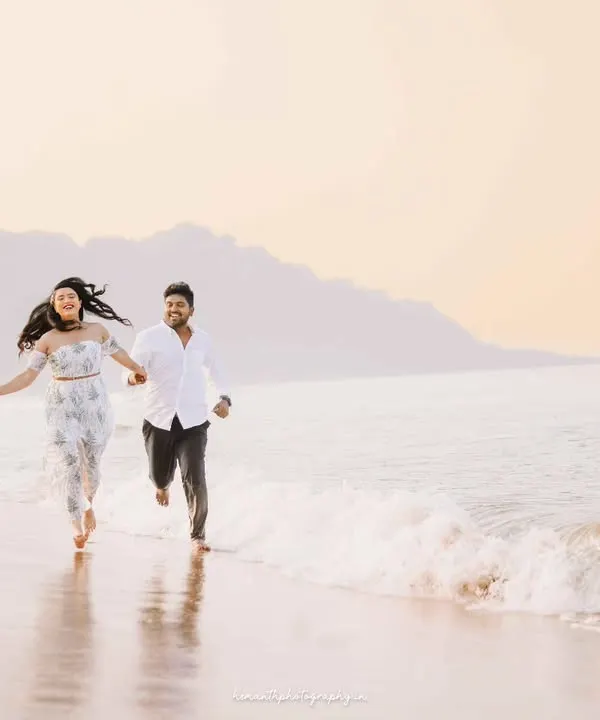 A couple runs joyfully along the shoreline at sunrise, hand in hand. This candid action shot captures their carefree energy against a soft, golden-hour backdrop.