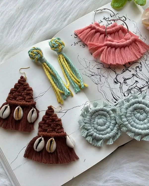 A showcase of the diverse earring styles I create by hand. This collection features brown tassel earrings with cowrie shells, two-tone knot and tassel earrings, soft pink fan-shaped fringe earrings, and light blue spiral designs, all laid out to show the intricate details of my boho jewelry.