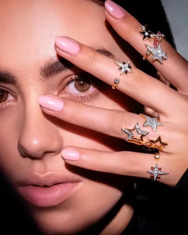A signature shot from the Farah Khan Atelier campaign, using a creative pose to highlight a stunning collection of star-themed rings. This is what high-end jewellery photography is all about.