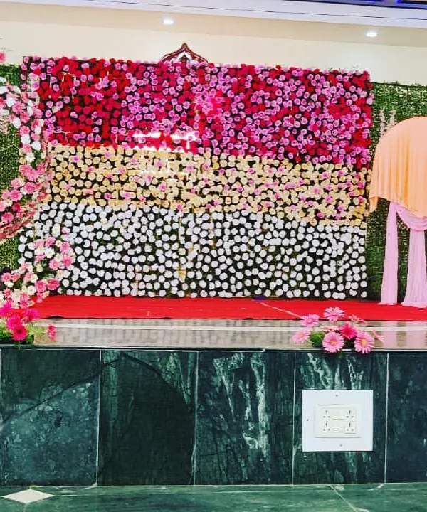A grand stage decoration featuring a full floral wall and a greenery wall with a spiral floral design. This creates a stunning and multi-dimensional backdrop.