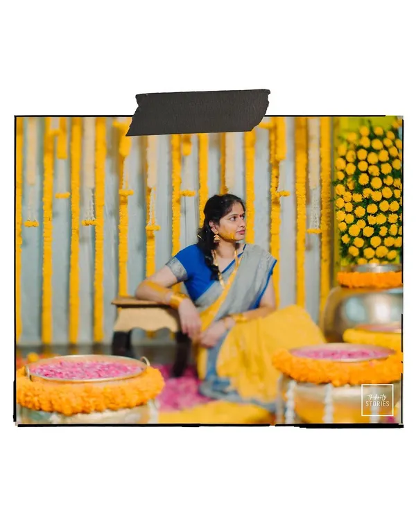 A candid shot of the bride during her Haldi ceremony, surrounded by marigold decorations, looking thoughtful and serene.