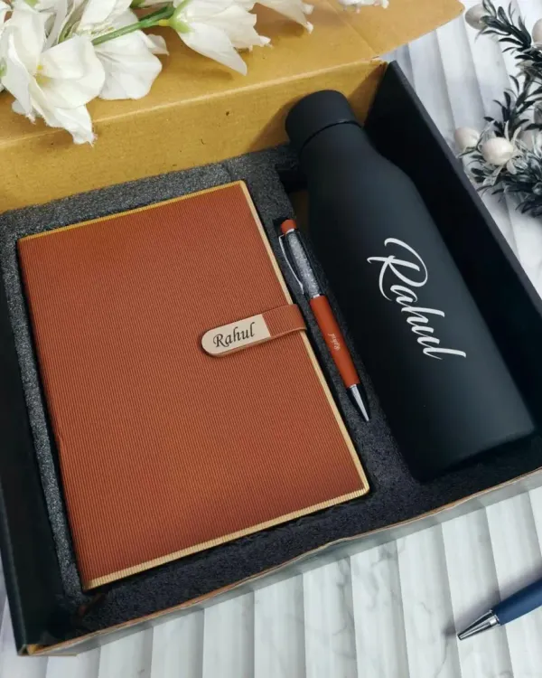 A classic personalized gift set, perfect for any professional. This combo includes a tan faux-leather diary with a name-engraved clasp, a matching pen, and a matte black temperature bottle with the name "Rahul" printed on it.