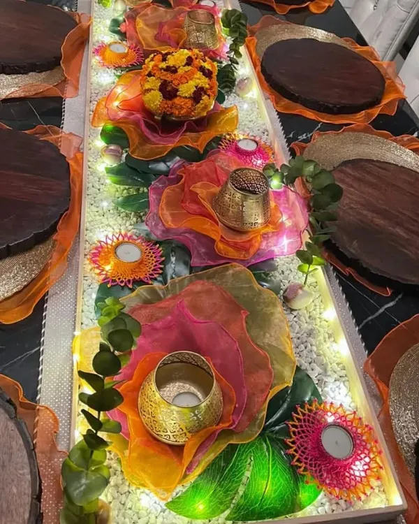 For this festive table, I used a runner of illuminated crystals and layered colorful organza to create a vibrant, glowing centerpiece. The design exudes a celebratory charm, with each hue dancing with joy under the warm lights.