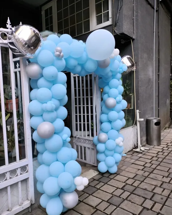 A beautiful balloon arch created for an event entrance. The design uses a soft light blue palette with pops of silver and white, creating a welcoming and elegant entryway for guests.