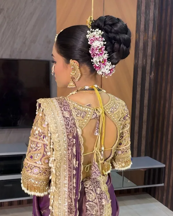 A close-up of a classic Maharashtrian bridal bun, intricately woven and adorned with fresh flowers and a pearl-studded pin.