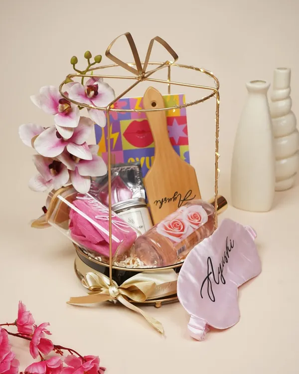 This birthday hamper for her is a dream in pink. It's curated with a personalized eye mask and hairbrush, a bottle of rosé wine, and other pampering goodies in a beautiful gold and black cage basket.