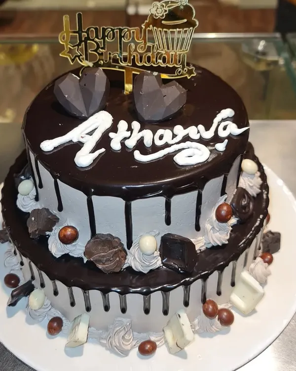 A decadent two-tier chocolate mousse cake. This rich cake is covered in chocolate ganache drips and topped with geometric chocolate hearts.
