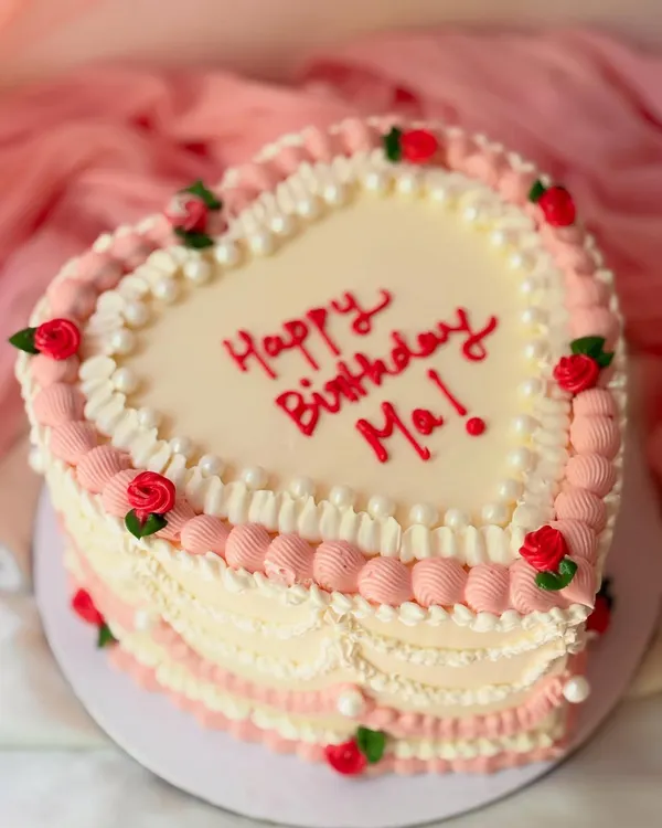 A classic heart-shaped cake for a mother's birthday. This design features vintage-style Lambeth piping in pink and white, with tiny piped red roses for a loving touch.