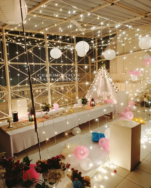 Here's a beautiful nighttime terrace setup I created. A canopy of fairy lights and hanging paper lanterns provides a magical glow over a long dinner table with comfortable floor seating.