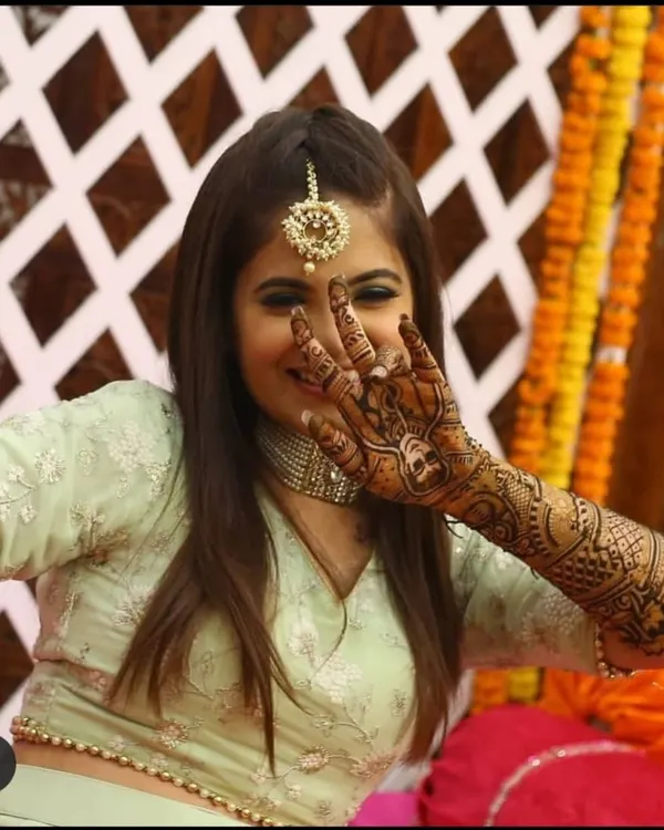 A happy bride playfully showing off her intricate bridal mehndi, her smile says it all.